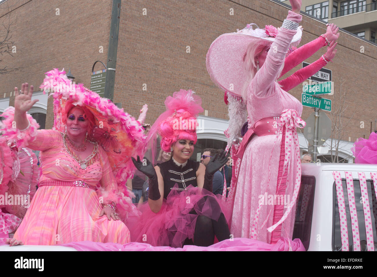 Rüschen kostümierte Damen in Rosa mit rosa Haut fahren und winken den Zuschauern während der Asheville, NC Karneval Parade Stockfoto