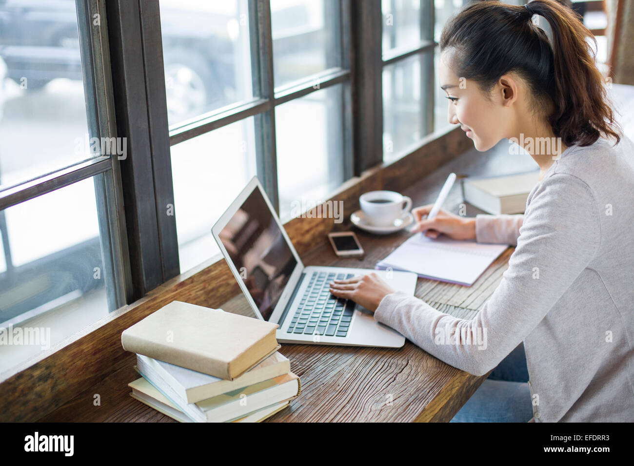 Junge Frau in Café studieren Stockfoto