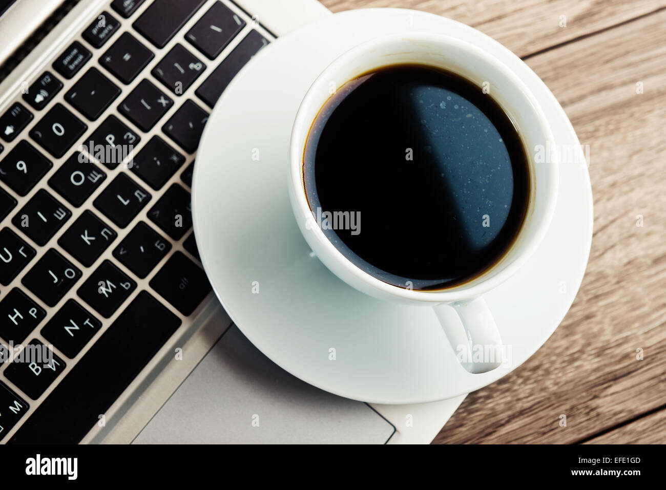 Tasse Kaffee und Laptop auf Holztisch. Stockfoto