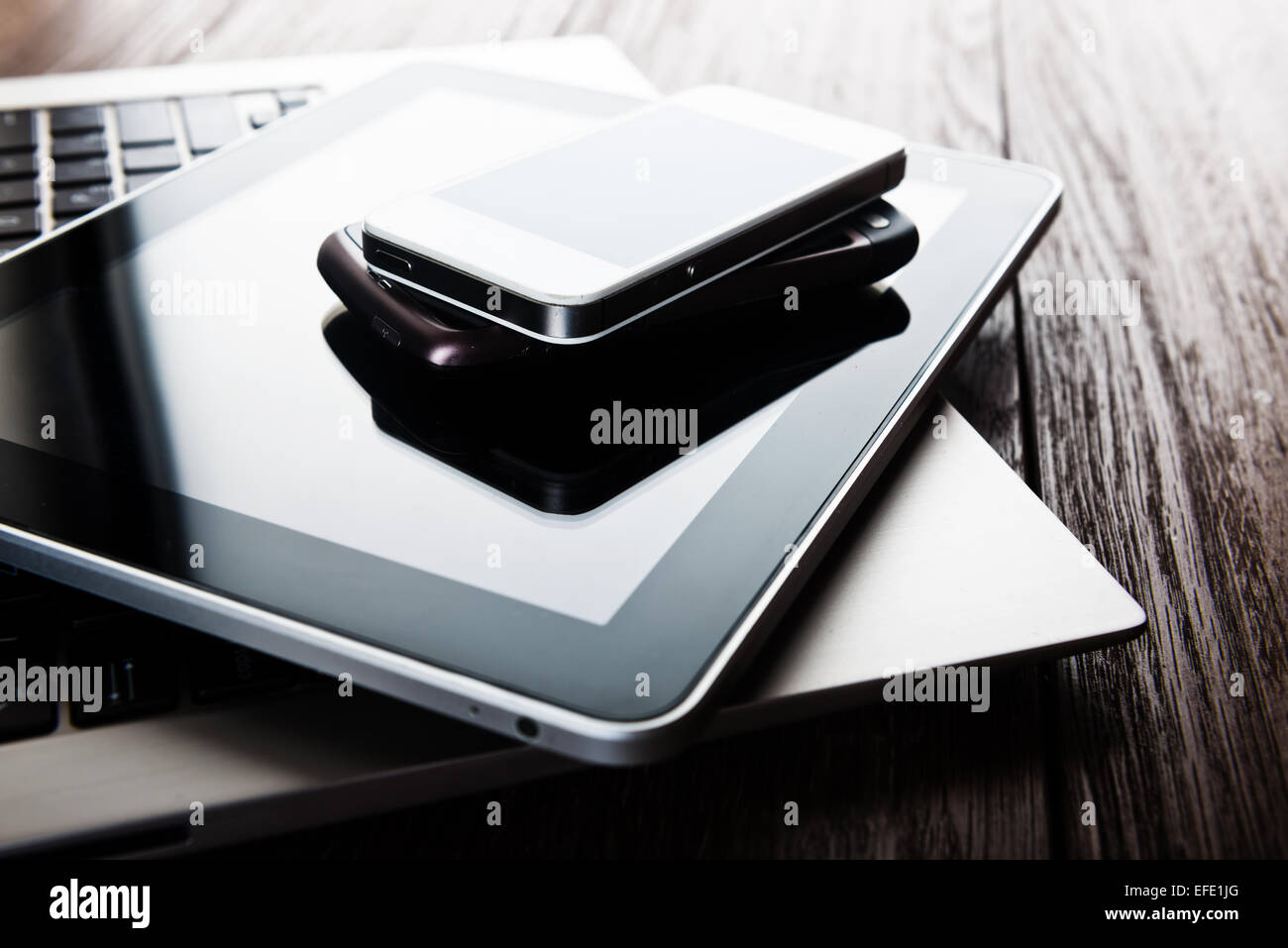 Tastatur mit zwei Handys und Tablet-pc am Schreibtisch aus Holz Stockfoto