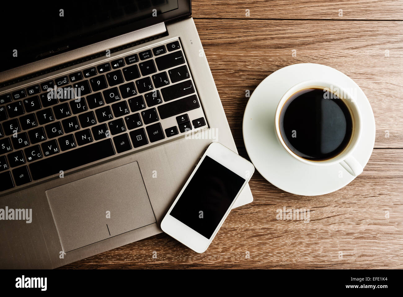 Büroarbeitsplatz mit Laptop auf hölzernen Schreibtisch mit Telefon und eine Tasse Kaffee zu öffnen Stockfoto