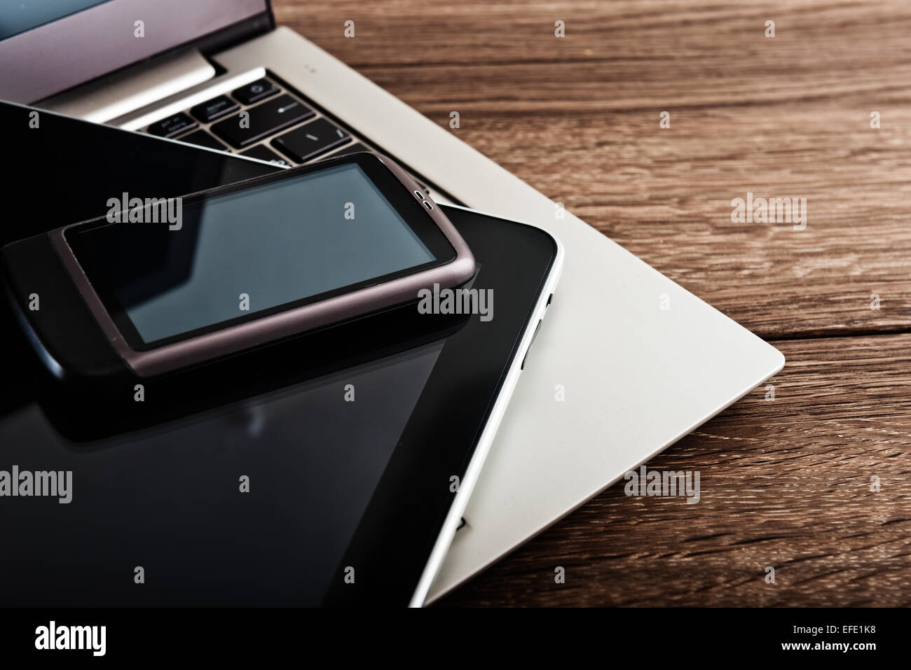 Tastatur mit Smartphone und Tablet pc am Schreibtisch aus Holz Stockfoto