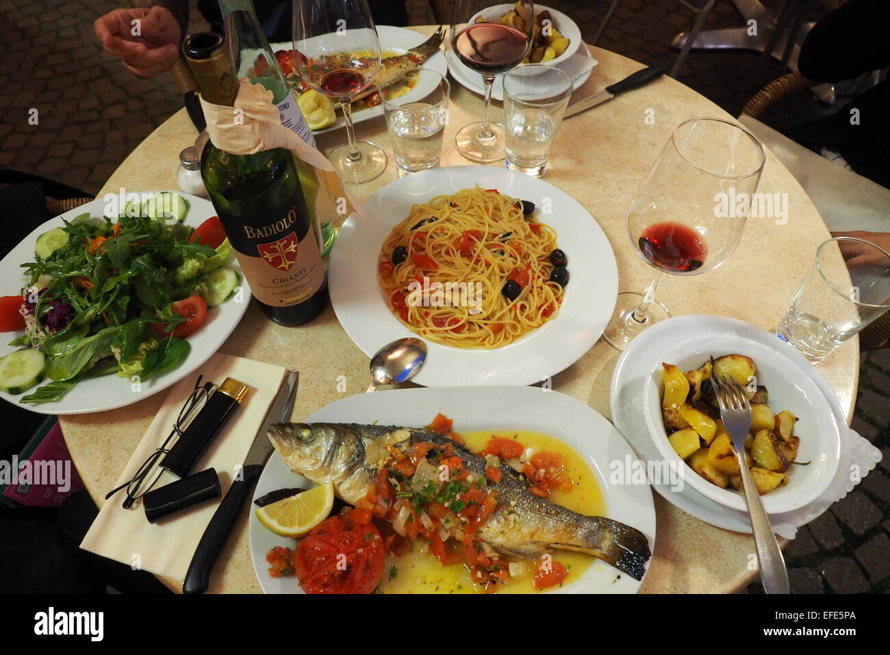Eine Mahlzeit mit ganzer Fisch, eine Schüssel mit Spaghetti und grünem Salat. Stockfoto