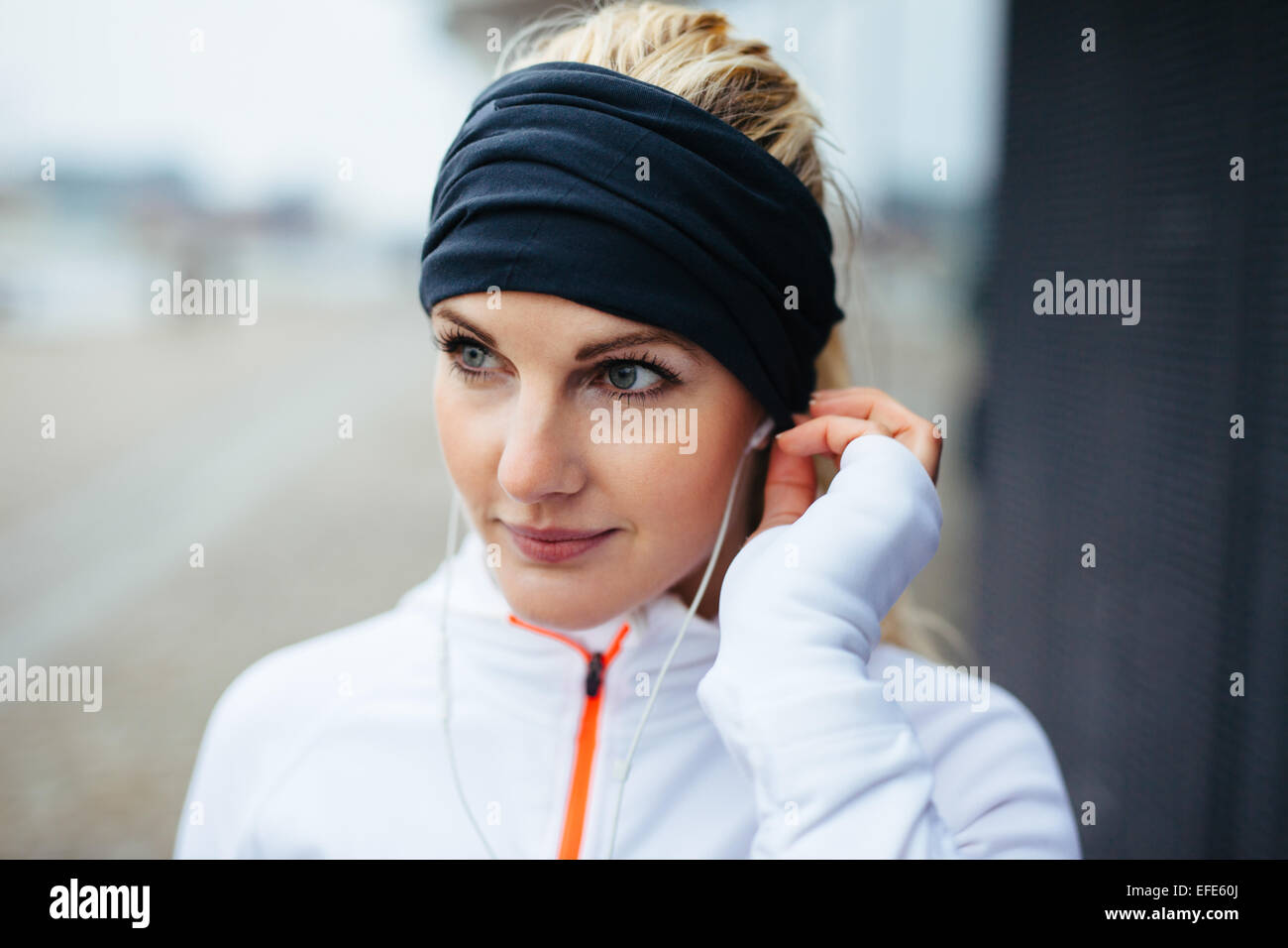 Close-up Portrait schöne Sportlerin Stirnband tragen und Musik über Kopfhörer hören. Fitness Frauen schauen entspannt Stockfoto