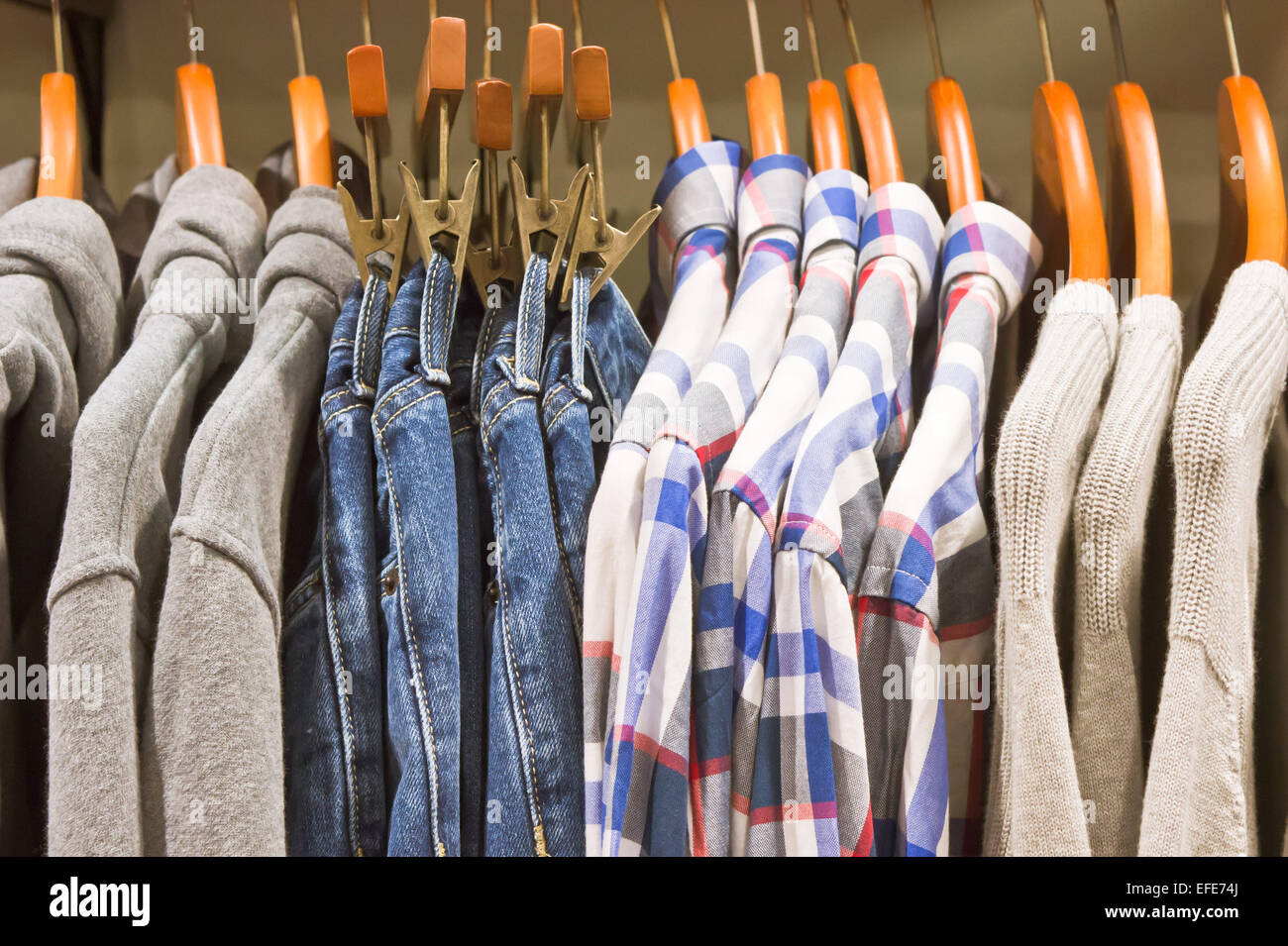 Lässige Pullover, Hosen und Hemden hängen in einem Geschäft Stockfoto