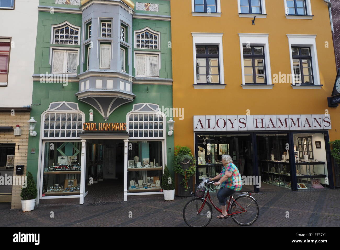 Eine ältere deutsche Dame, die mit dem Fahrrad vor bunten Geschäften in  Xanten, Deutschland Stockfotografie - Alamy