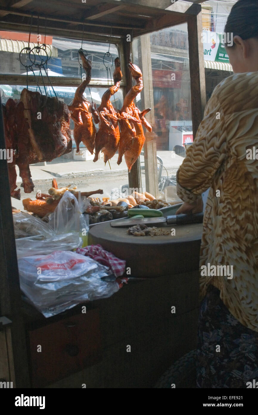 Eine Frau verkauft gebratene Enten, die auf einem mobilen Lebensmittel-Wagen auf einer Stadtstraße in Kampong Cham, Kambodscha hängen. Stockfoto
