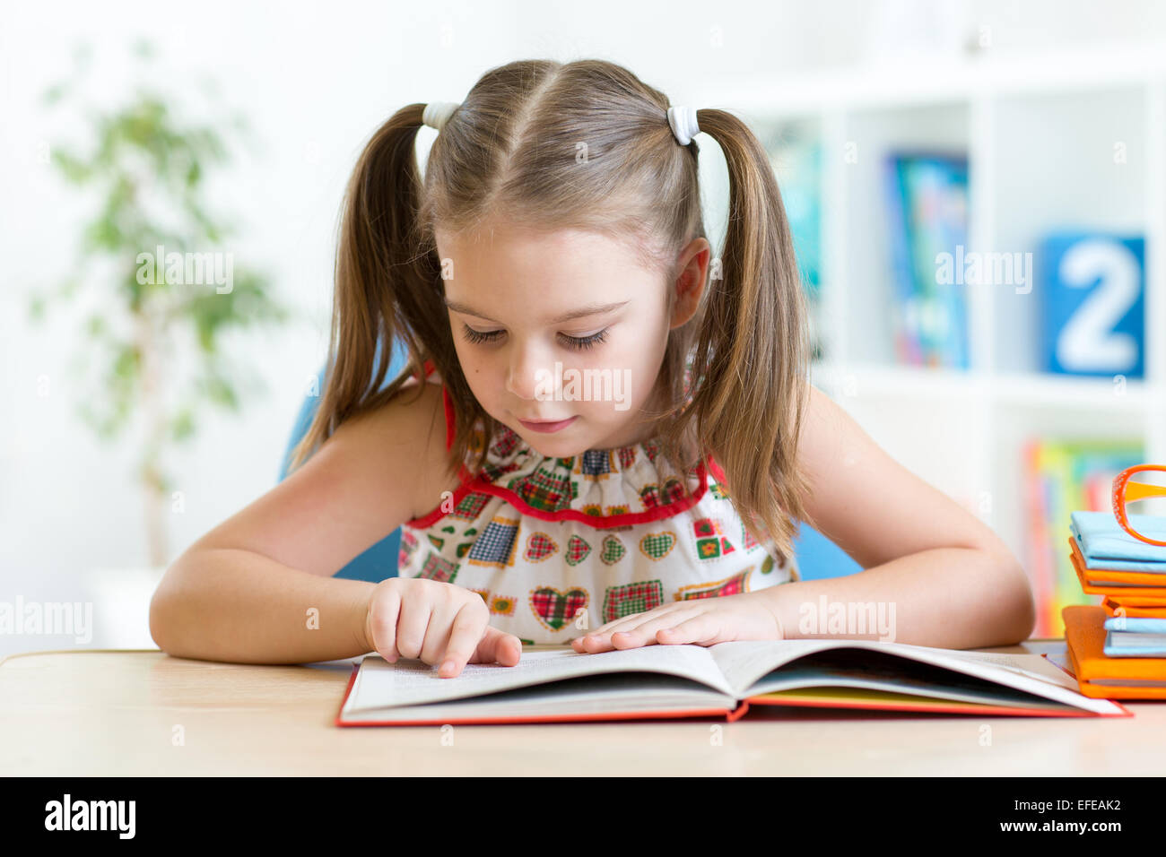 Niedliche kleine Mädchen lesen Geschichte aus großen Buch im Kindergarten Stockfoto