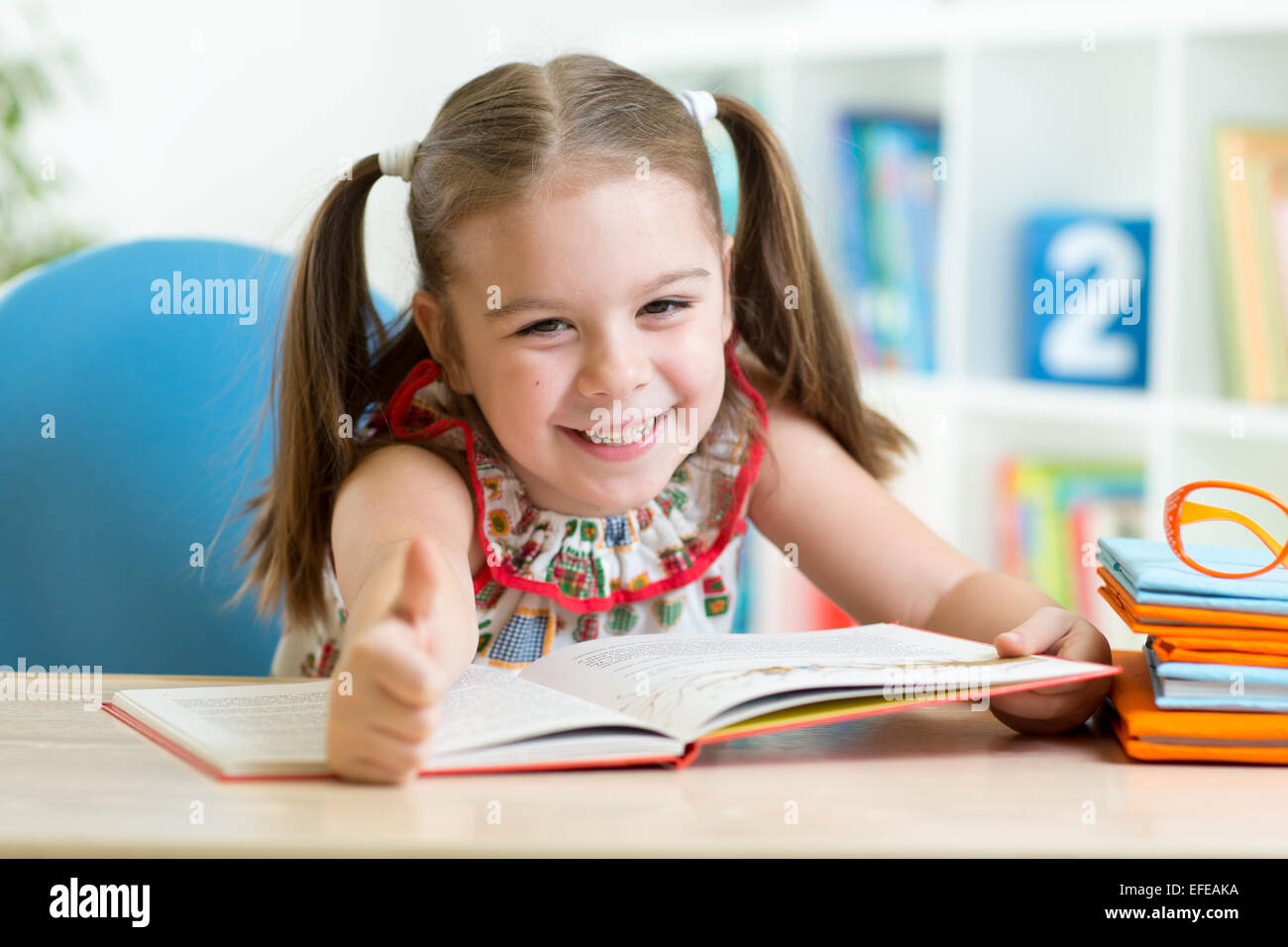 Kind Mädchen lesen Geschichte aus großen Buch im Kindergarten Stockfoto