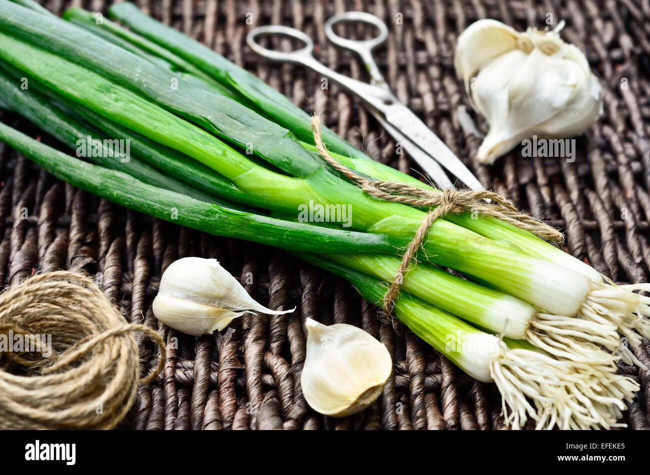 Frühlingszwiebeln und Knoblauch auf Korbwaren Tablett Stockfoto