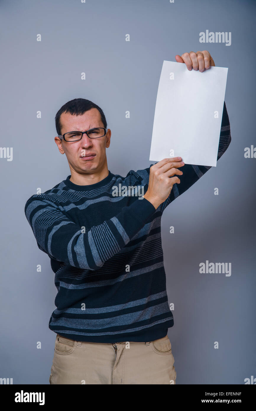Europäisch anmutende Mann von 30 Jahren hält ein leeres Blatt, resentme Stockfoto
