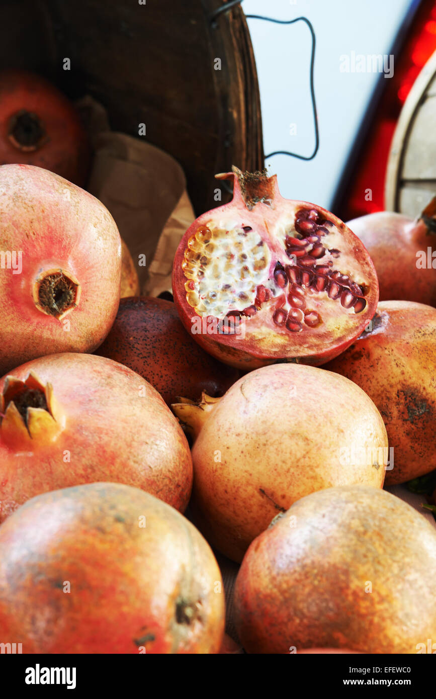 Granatapfel aufschneiden am Bauernmarkt sitzt auf einem Stapel von ganzen Granatäpfel Stockfoto