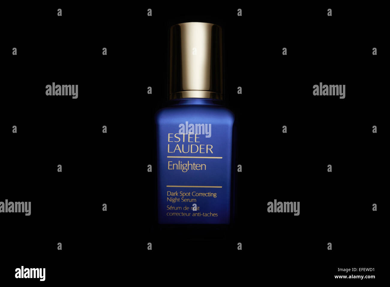 Estee Lauder erleuchten, blaue Flasche mit gold Top kommen aus der Dunkelheit Stockfoto