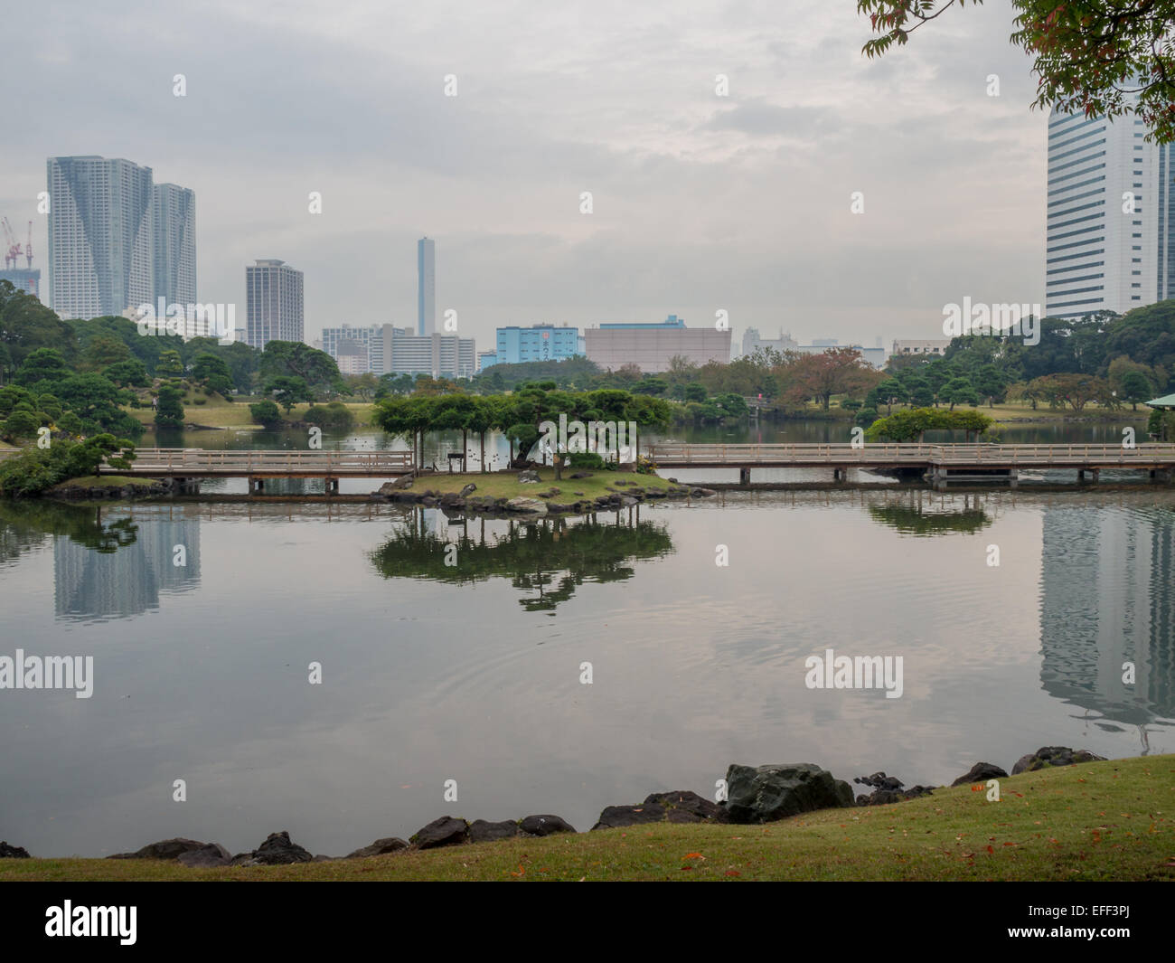 Japanische Gartenlandschaft und Wolkenkratzer spiegelt sich im Wasser am Hama-Rikyu Onshi-teien Stockfoto