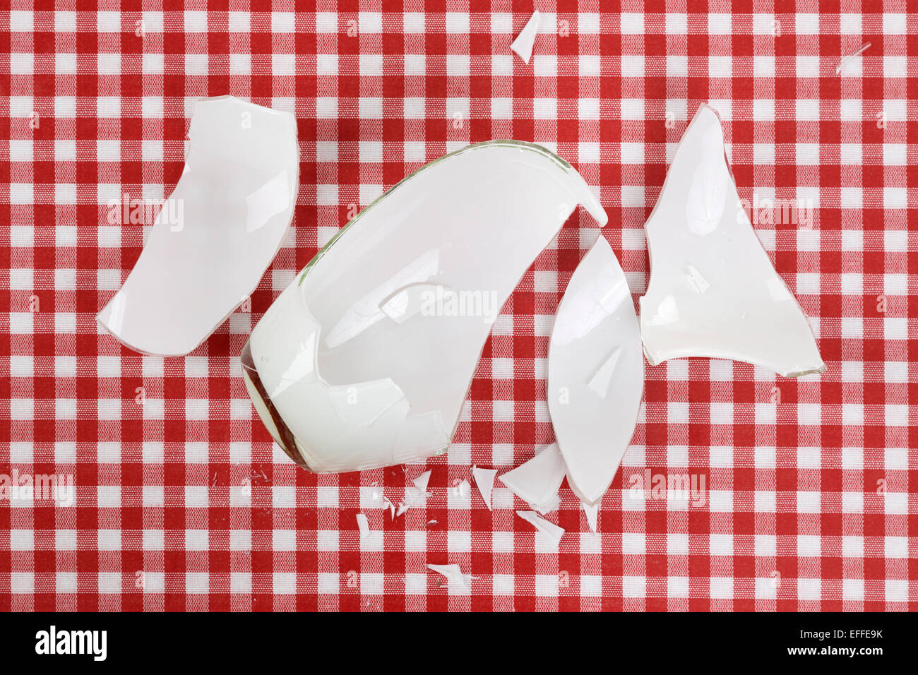 Stücke gebrochene weiße Blumenvase auf aufgegebenes Tuch rot-weiß Stockfoto