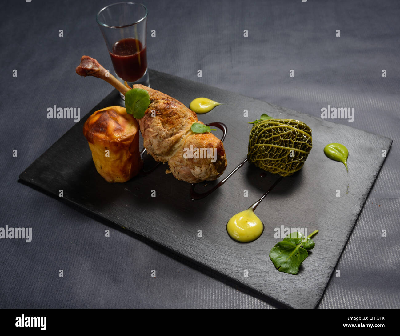 Confit gefüllte Entenkeule mit Cranberry Kohl Kugel und Schwede Fondant und Johannisbeer-Sauce auf einem Teller Schiefer Stockfoto