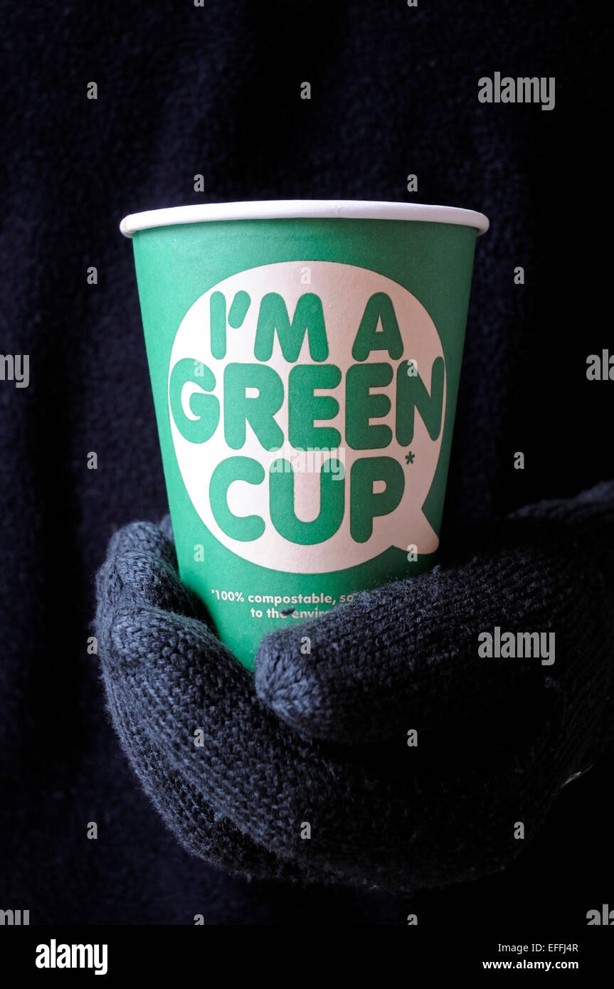 Ich bin eine grüne Tasse gedruckt auf der Vorderseite eine 100 % kompostierbar Pappbecher Art für die Umwelt. In Mannes behandschuhten Hand gehalten Stockfoto