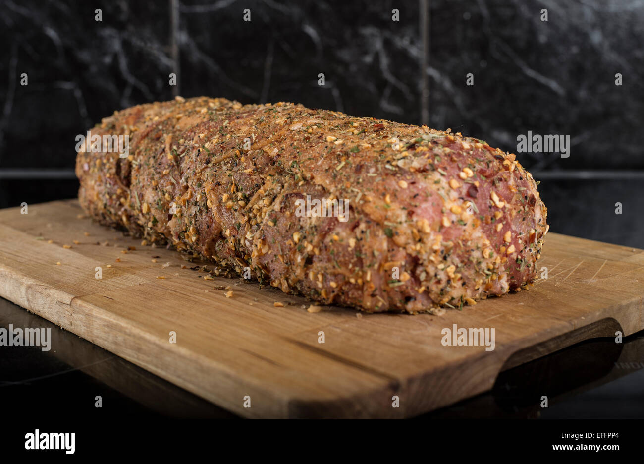 Schweinefilet umhüllt mit Speck und Kräutern auf Holzbrett Stockfoto