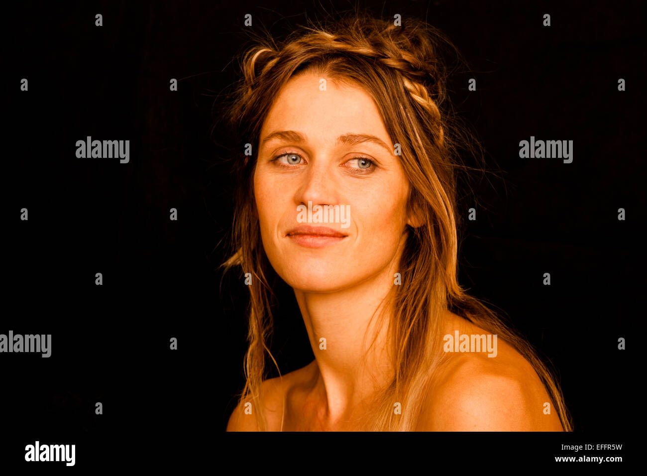 Porträt der lächelnde Frau mit Zopf vor schwarzem Hintergrund Stockfoto