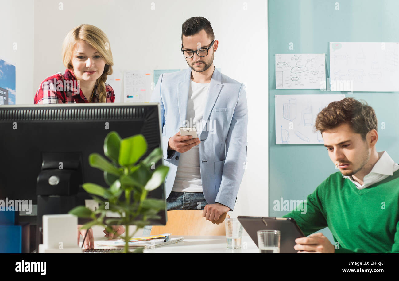 Drei junge Leute im Büro mit Computer-monitor Stockfoto