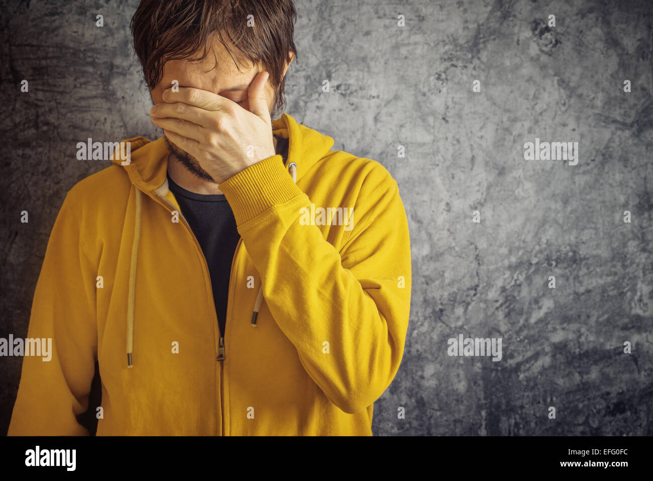 Erwachsenen Menschen mit chronischer Migräne-Kopfschmerzen, die gelbe Jacke tragen. Stockfoto