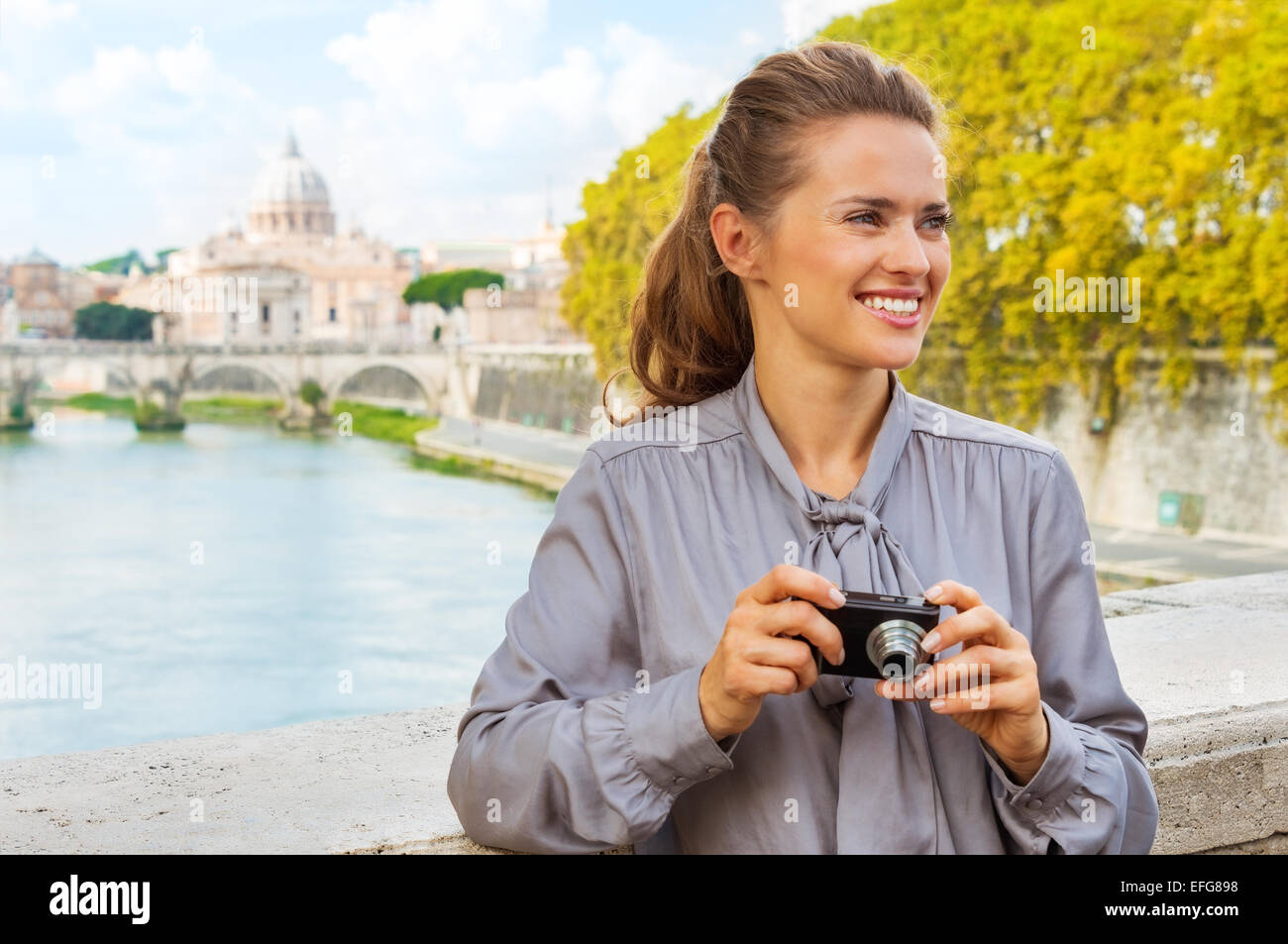 Porträt der glückliche junge Frau mit Foto-Kamera während der Brücke Ponte Umberto I mit Blick auf die Basilica di San Pietro Stockfoto