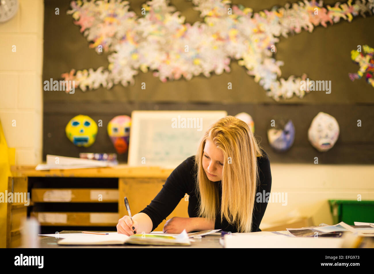 Ein junges Mädchen arbeitet und schreibt ihre Kursarbeit in einem Jahr 13 Kunstunterricht an einer weiterführenden Schule, Wales UK Stockfoto