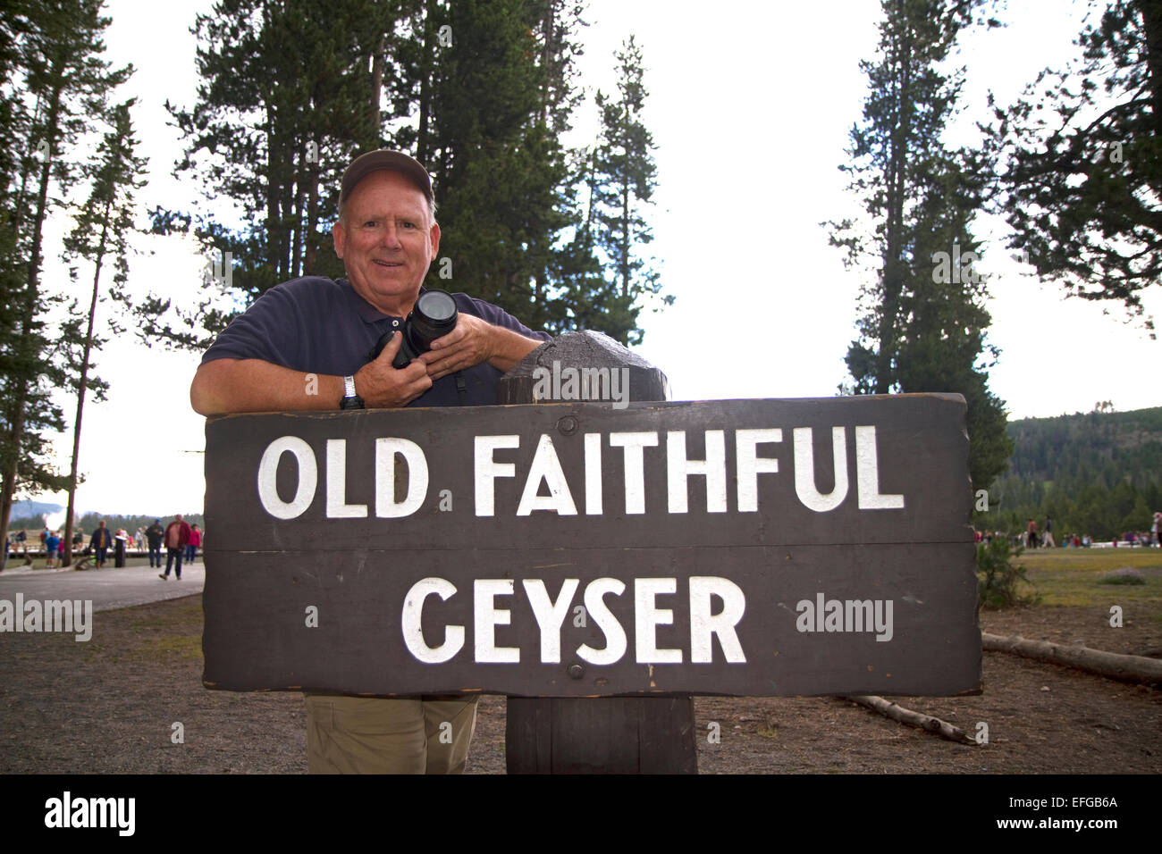 David R. Frazier stehen bei den Anzeichen für Old Faithful Geysir im Yellowstone-Nationalpark, Wyoming, USA. Stockfoto