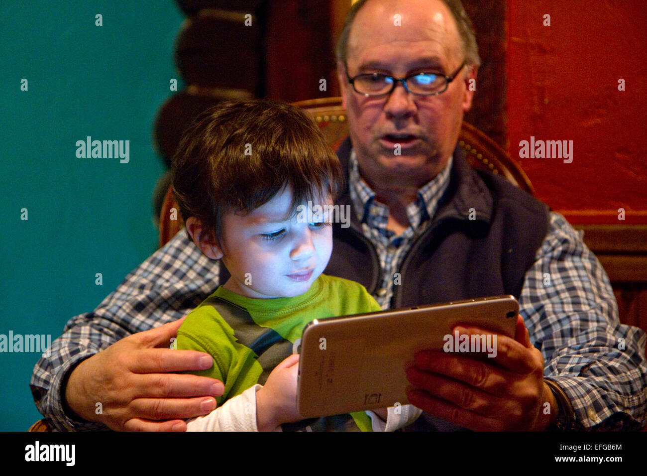 Mann liest aus einem iPad Tablette, ein kleiner Junge in Boise, Idaho, USA. Stockfoto
