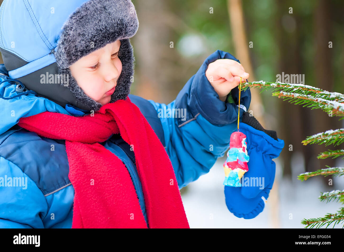 junge hängt die Christbaumkugeln im Wald Stockfoto