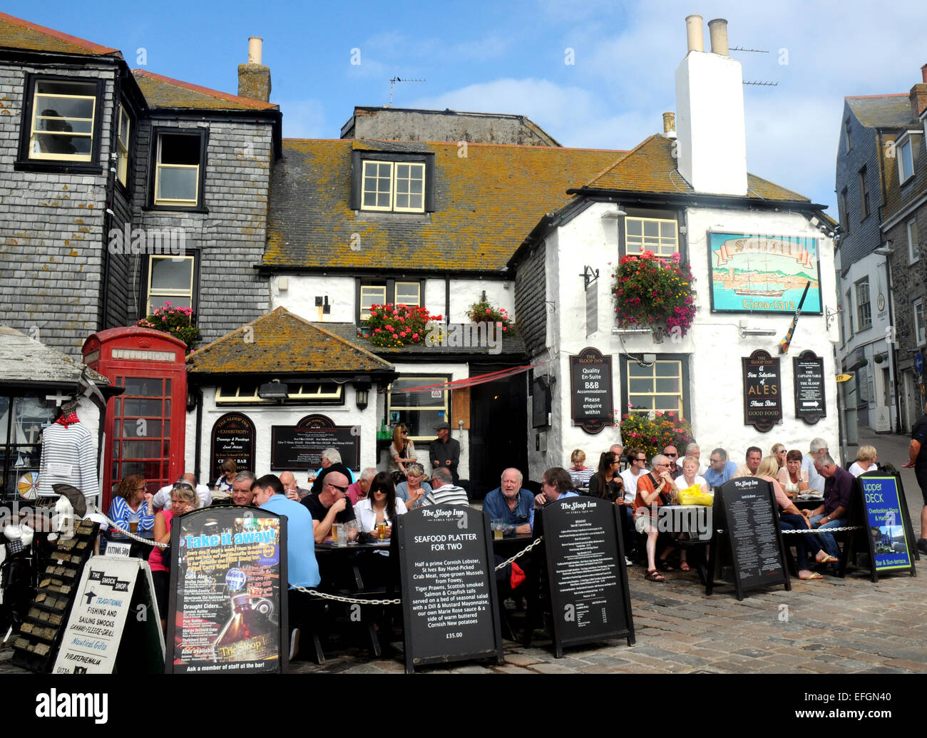 Genießen die Sonne außerhalb der Sloop Inn at St. Ives, Cornwall. Stockfoto