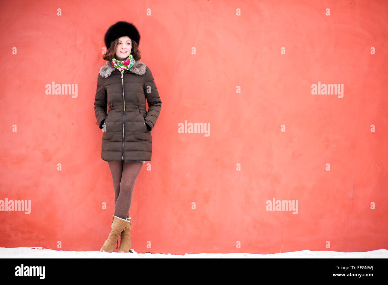 Frau steht in einer guten Stimmung in der Nähe der roten Wand Stockfoto