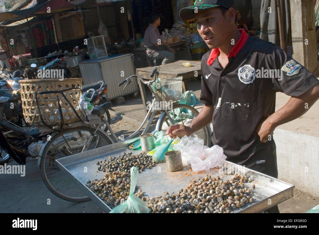 Ein Mann verkauft Schnecken als Straße Nahrung auf eine Stadt Straße in Kampong Cham, Kambodscha. Stockfoto