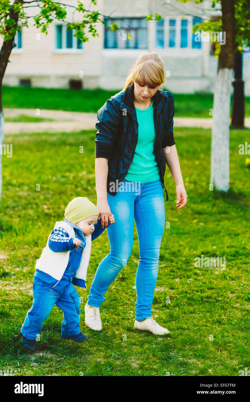 Erste Schritte-Baby mit ihrer Mutter In den Frühling-Ausflug. Kleiner Junge bei Spaziergang im Frühling Stockfoto