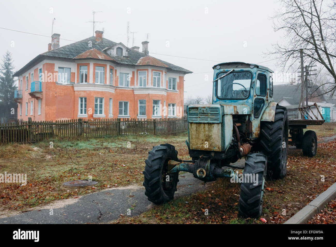 Alten sowjetischen rostigen Ackerschlepper Parken auf dem Bürgersteig in der Nähe von rotem Backstein-Haus in Dobrush, Region Gomel, Weißrussland Stockfoto