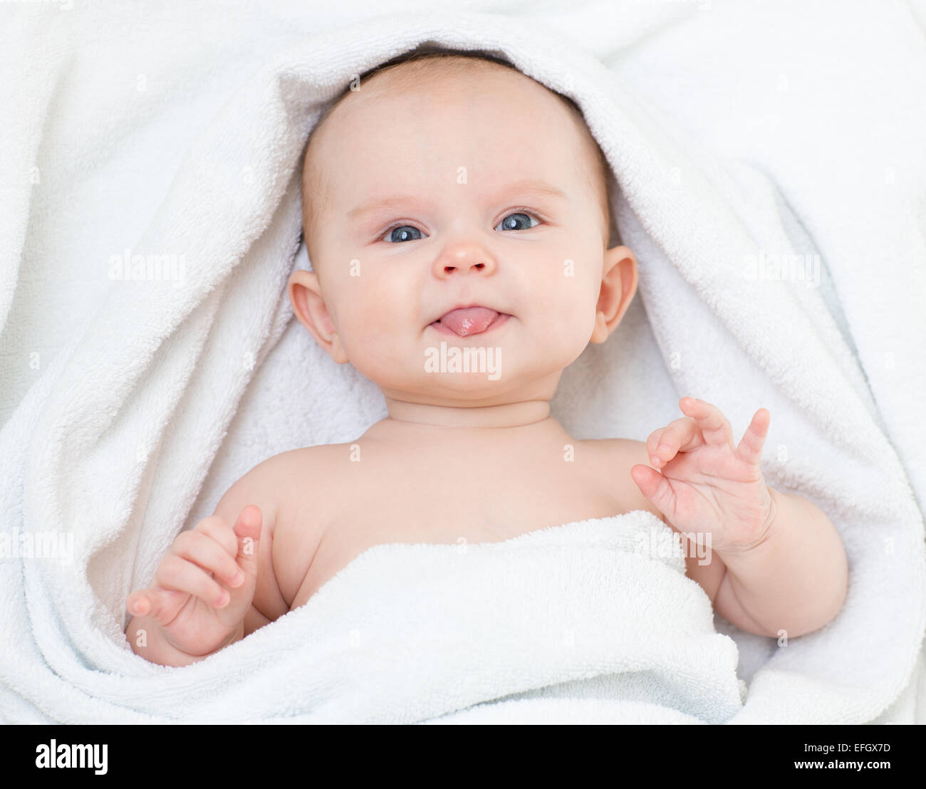 Süße lustige Baby in Baden Handtuch mit Zunge Stockfoto