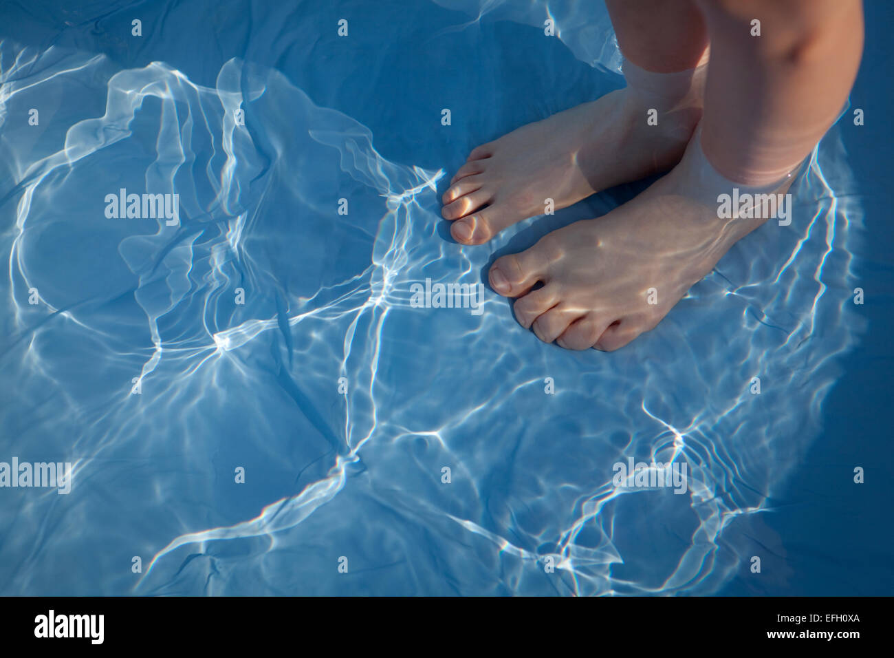 Füße des Kindes unter dem klaren, blauen Wasser der ein Planschbecken verzerrt. Stockfoto