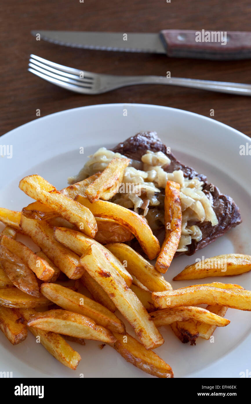 Beefsteak, Pommes Frites und Schalotten auf einem Teller Stockfoto