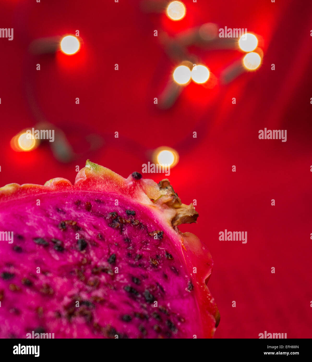 leckere lebendigen Drachenfrucht Pitaya mit rosa Fleisch auf rotem Grund mit Lichtern Stockfoto