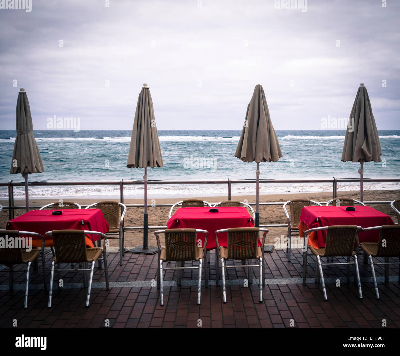 Leere Tische und Stühle im freien Restaurant mit Blick auf Strand. Stockfoto
