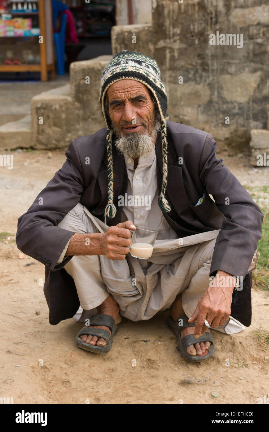 Alter Mann hocken, während Teetrinken in Chisapani Village auf der Royal Trek, in der Nähe von Pokhara, Nepal Stockfoto