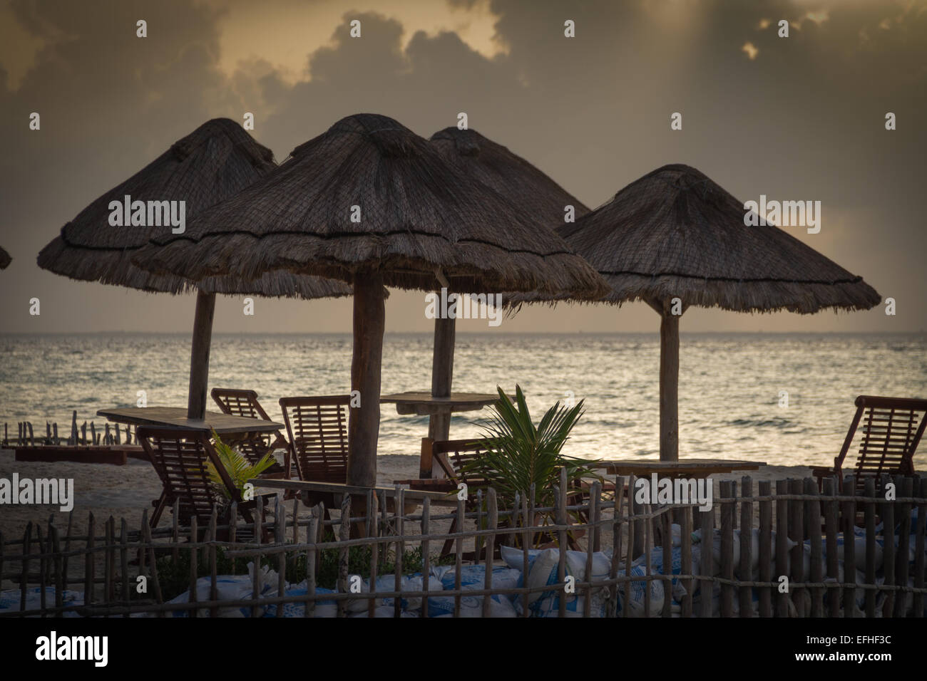 Eine Gruppe von Stühlen und Tischen am Strand bei Sonnenuntergang Stockfoto