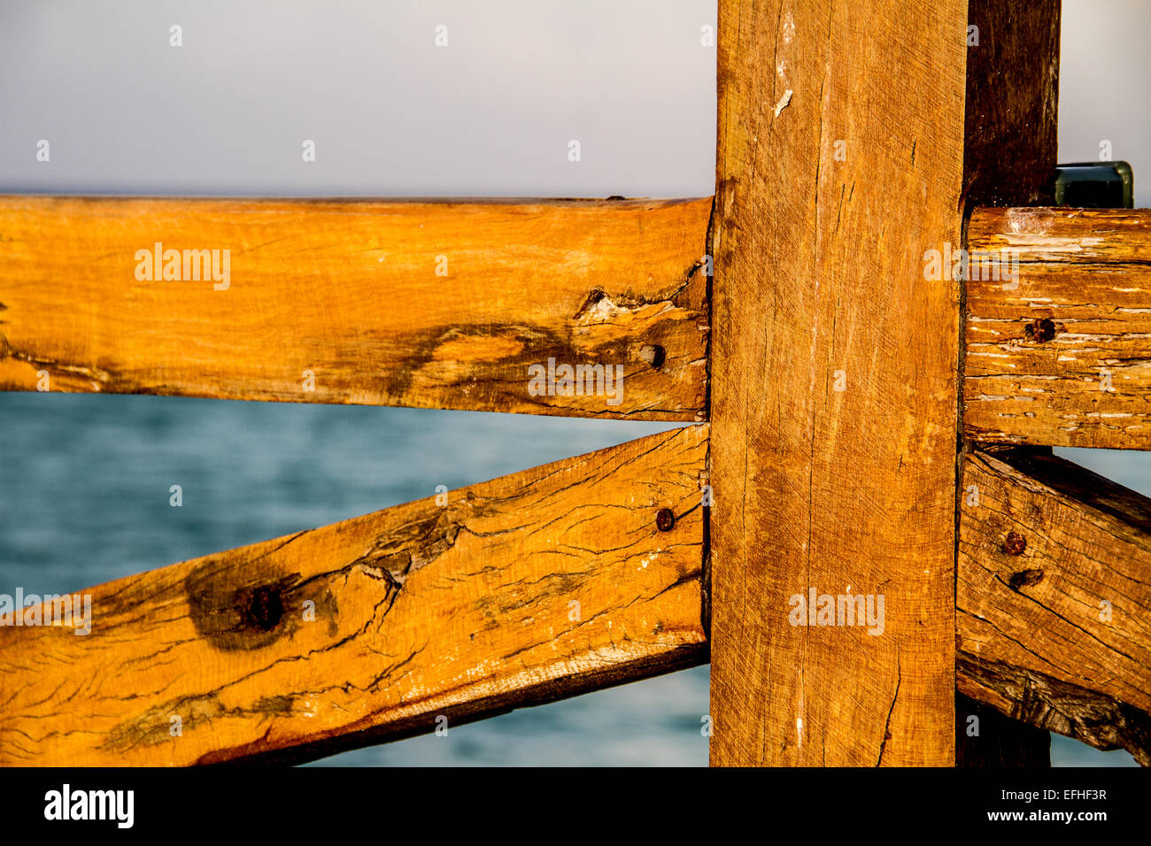 Textur der Holzpfosten von einer Brücke bei einem Pier und blauen Meer als Hintergrund Stockfoto