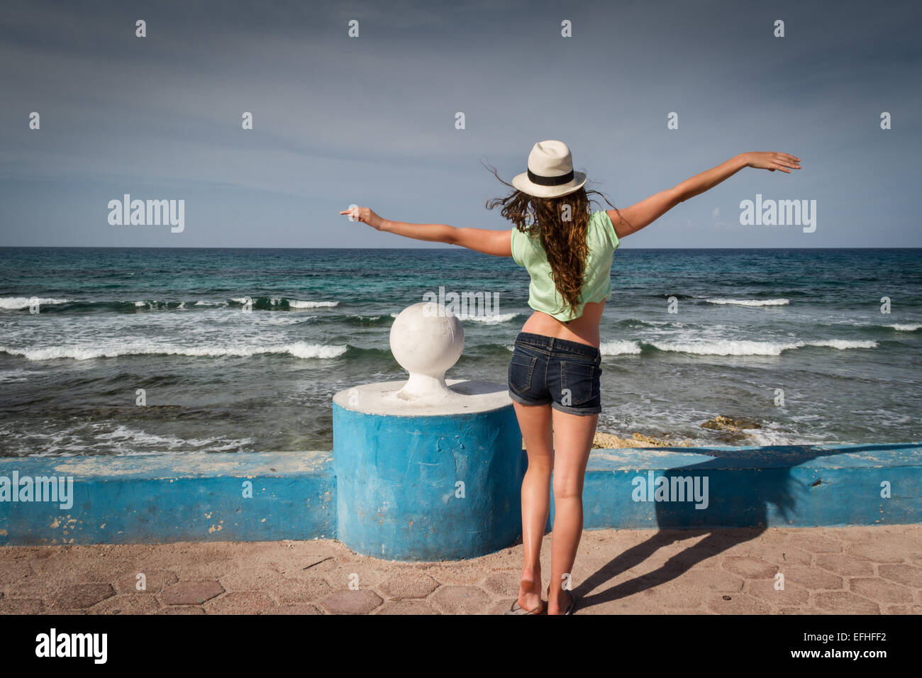 Junge Frau in einem Sommeroutfit genießen die Brise vom Meer entfernt Stockfoto