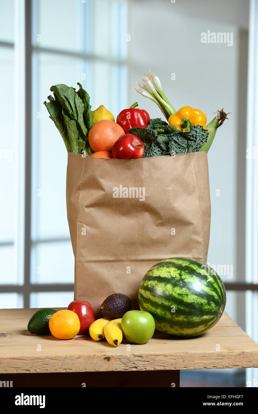 Obst und Gemüse in Einkaufstüte und auf Holztisch Stockfoto