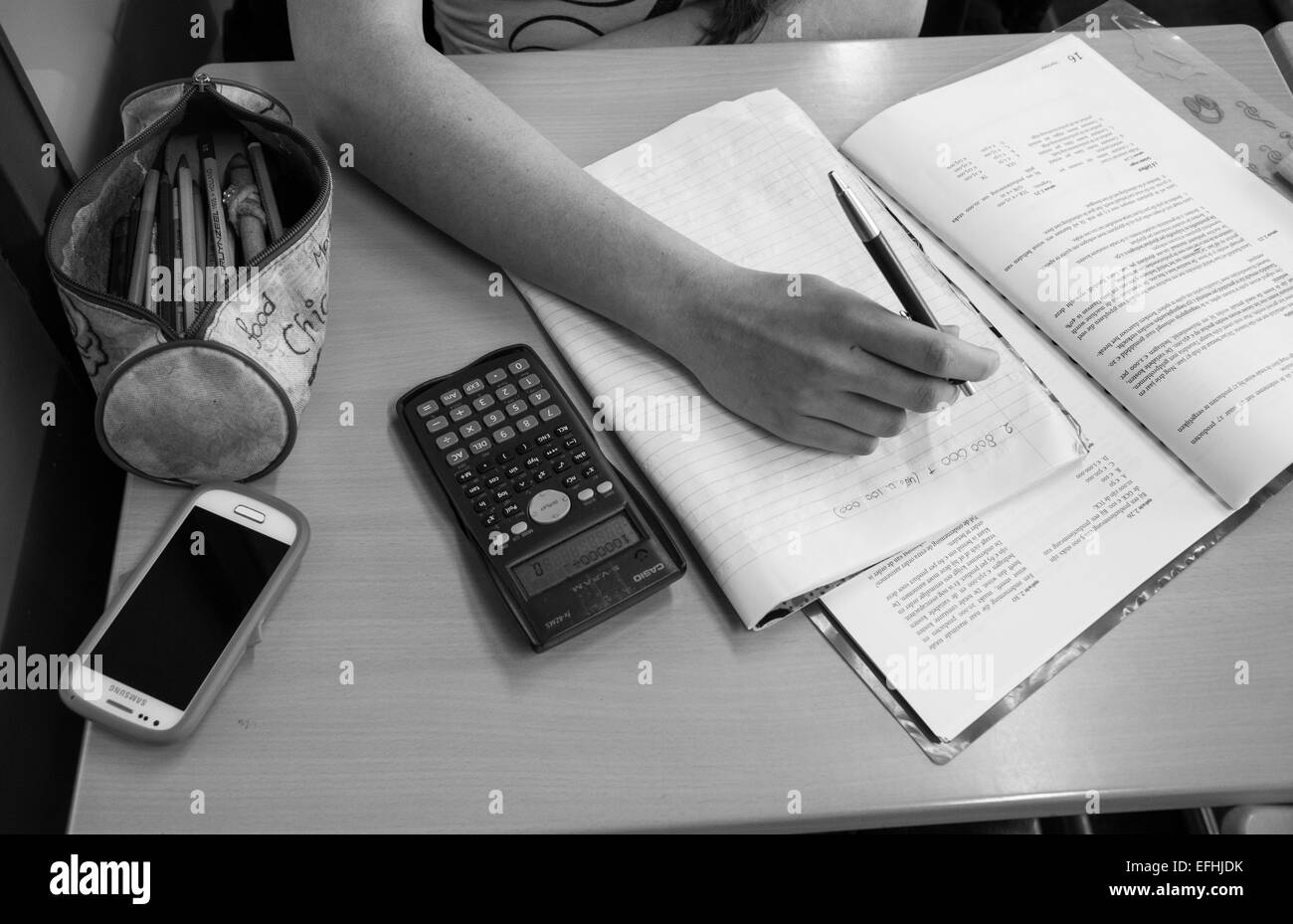 Hand des Mädchens schreiben Hausaufgaben an einem Tisch im Klassenzimmer Stockfoto