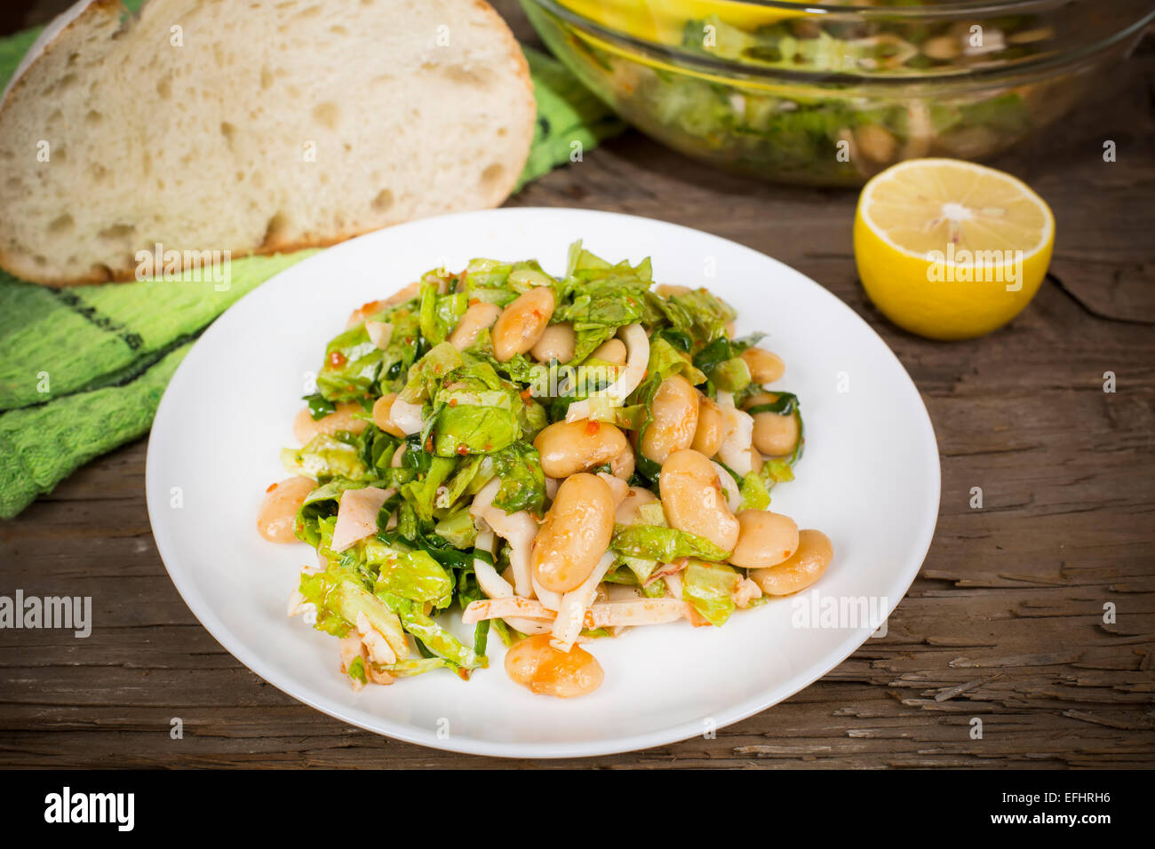 Salat mit Bohnen und Tintenfisch in einer Schüssel auf dem alten Tisch Stockfoto