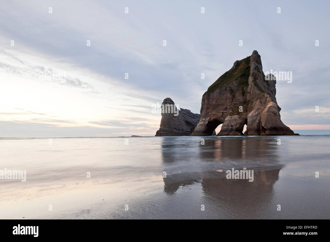 Torbogen Inseln und Strand bei Ebbe, Reflexion im Wasser, Wharariki Beach, Südinsel, Neuseeland Stockfoto