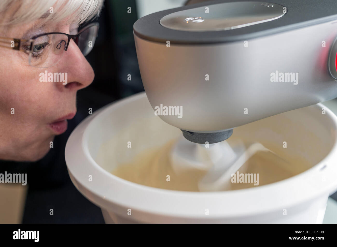 Frauenkopf mit weit aufgerissenen Augen Blick auf ihre Küchenmaschine, Deutschland Stockfoto