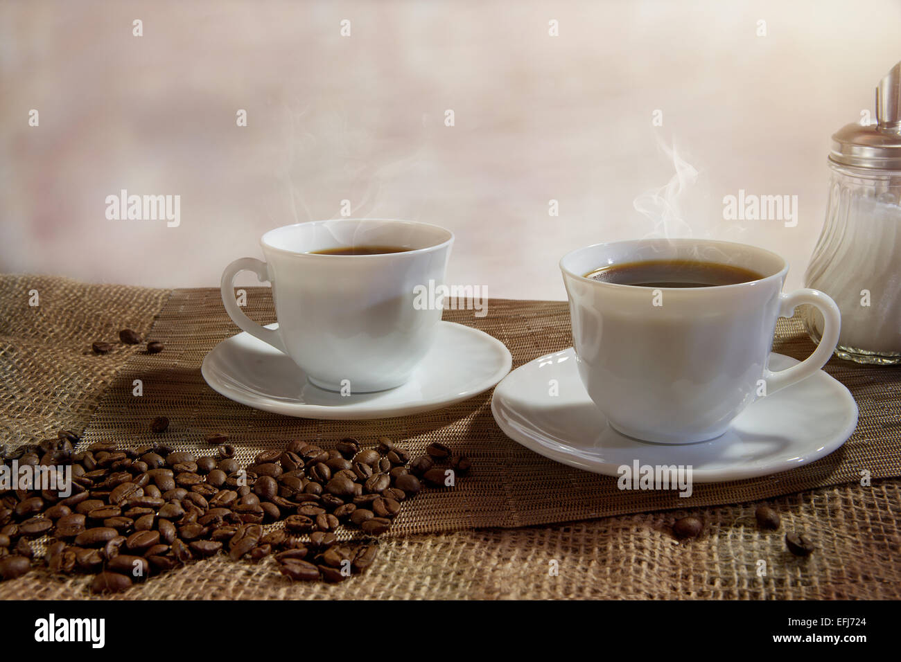 Zwei Tassen dampfendem Kaffee, Kaffeebohnen vor Stockfoto